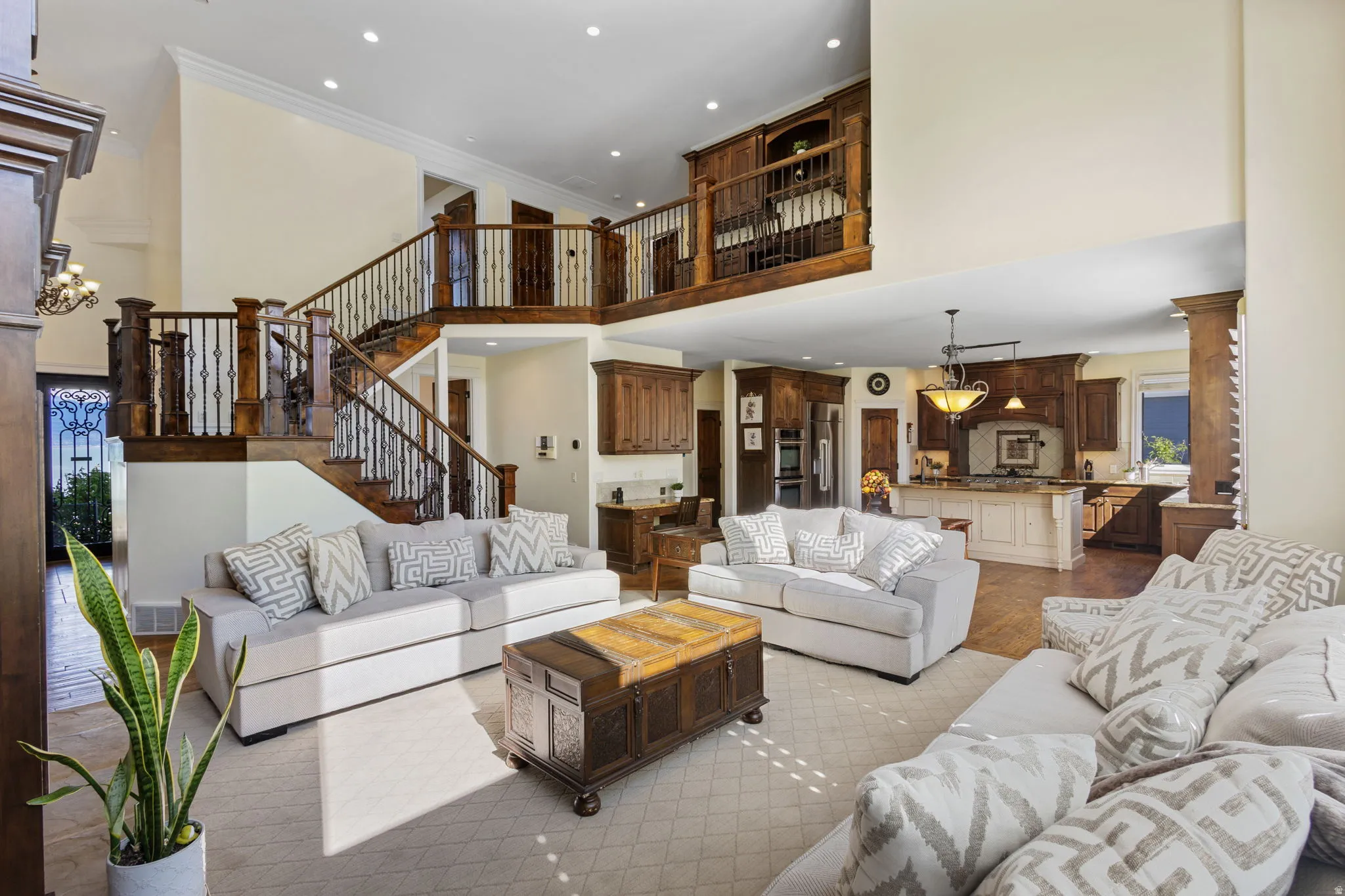 Living area featuring decorative columns, a high ceiling, crown molding, wood finished floors, and hanging lights