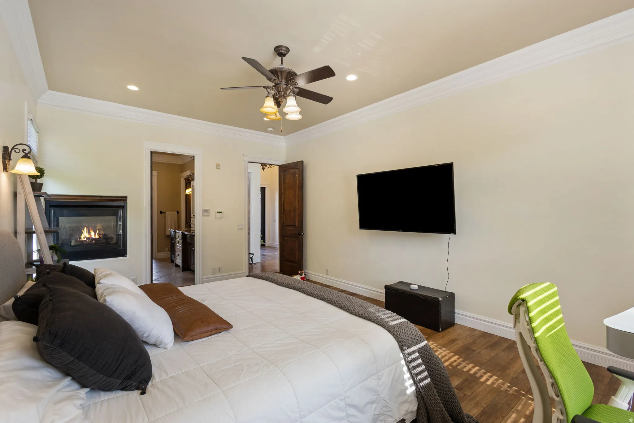 Bedroom with crown molding, a glass covered fireplace, a ceiling fan, wood finished floors, and recessed lighting