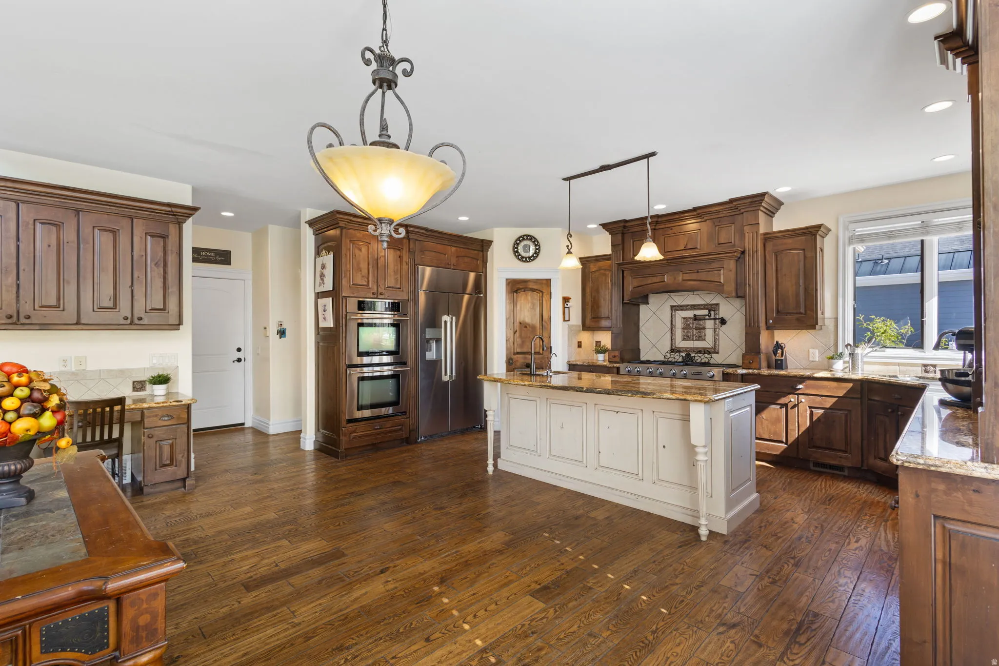 Dual tone kitchen featuring dark wood finished floors, dark stone countertops, stainless steel appliances, decorative backsplash, and dual tone cabinetry