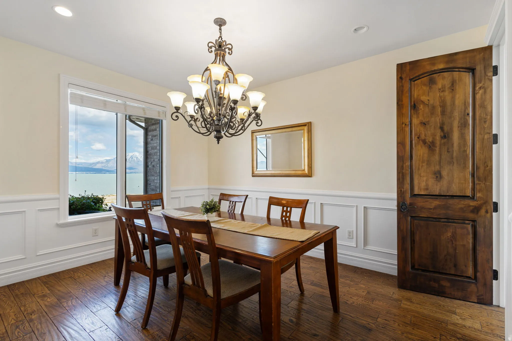 Dining space featuring plenty of natural light, dark wood-style flooring, a wainscoted wall, a decorative wall, and a chandelier