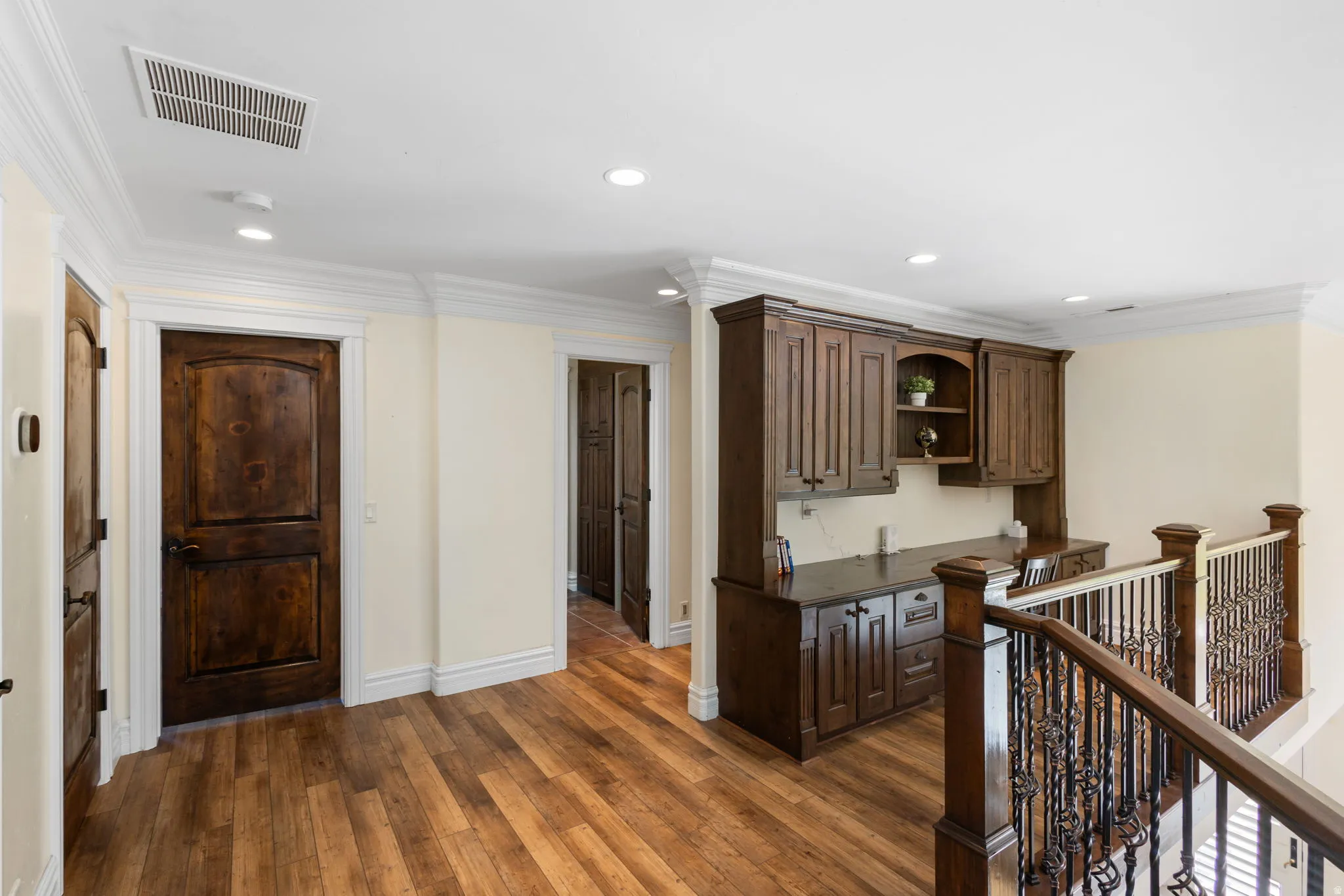 Corridor featuring ornamental molding, dark wood finished floors, recessed lighting, and an upstairs landing
