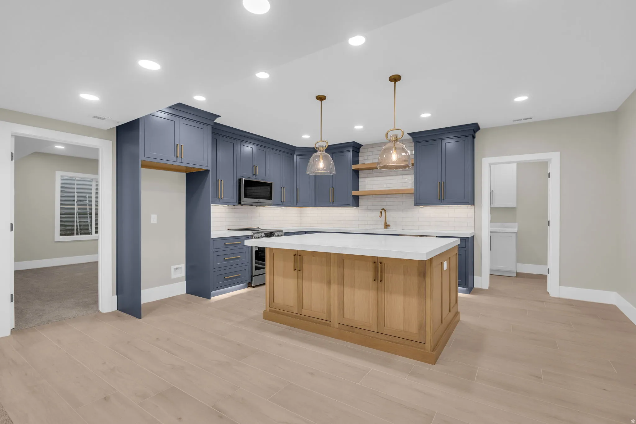 Modern kitchen with blue cabinetry, white subway tile backsplash, and wood-finish flooring