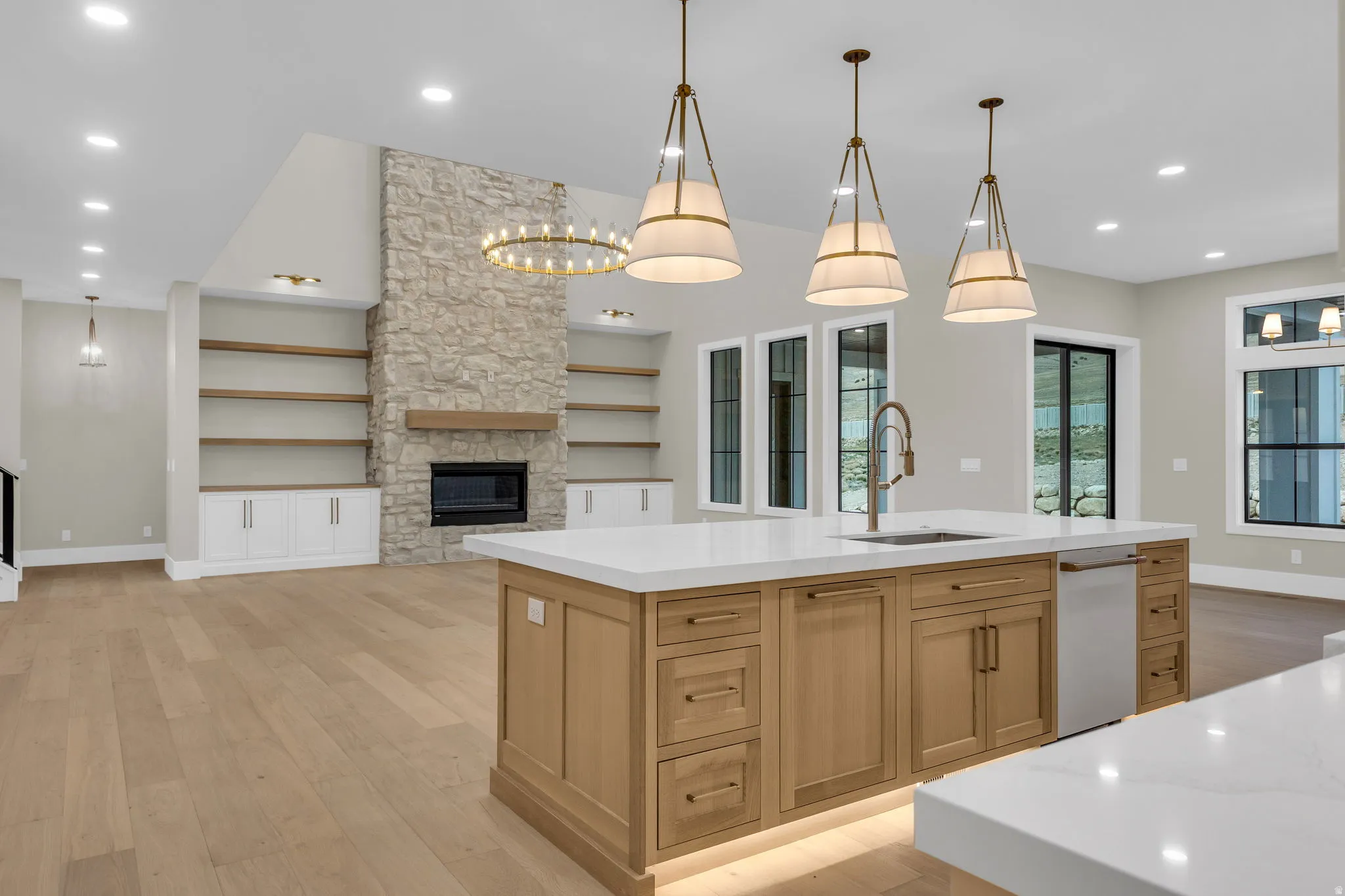 Gourmet kitchen island with white countertops, integrated sink, and undermount lighting