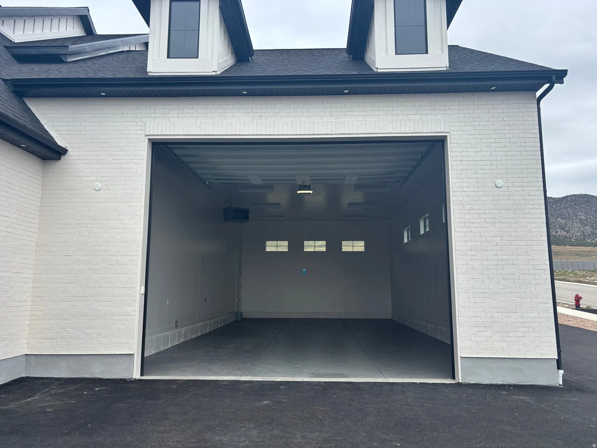 Spacious three-car garage featuring a concrete floor, painted walls, and transom windows for natural light