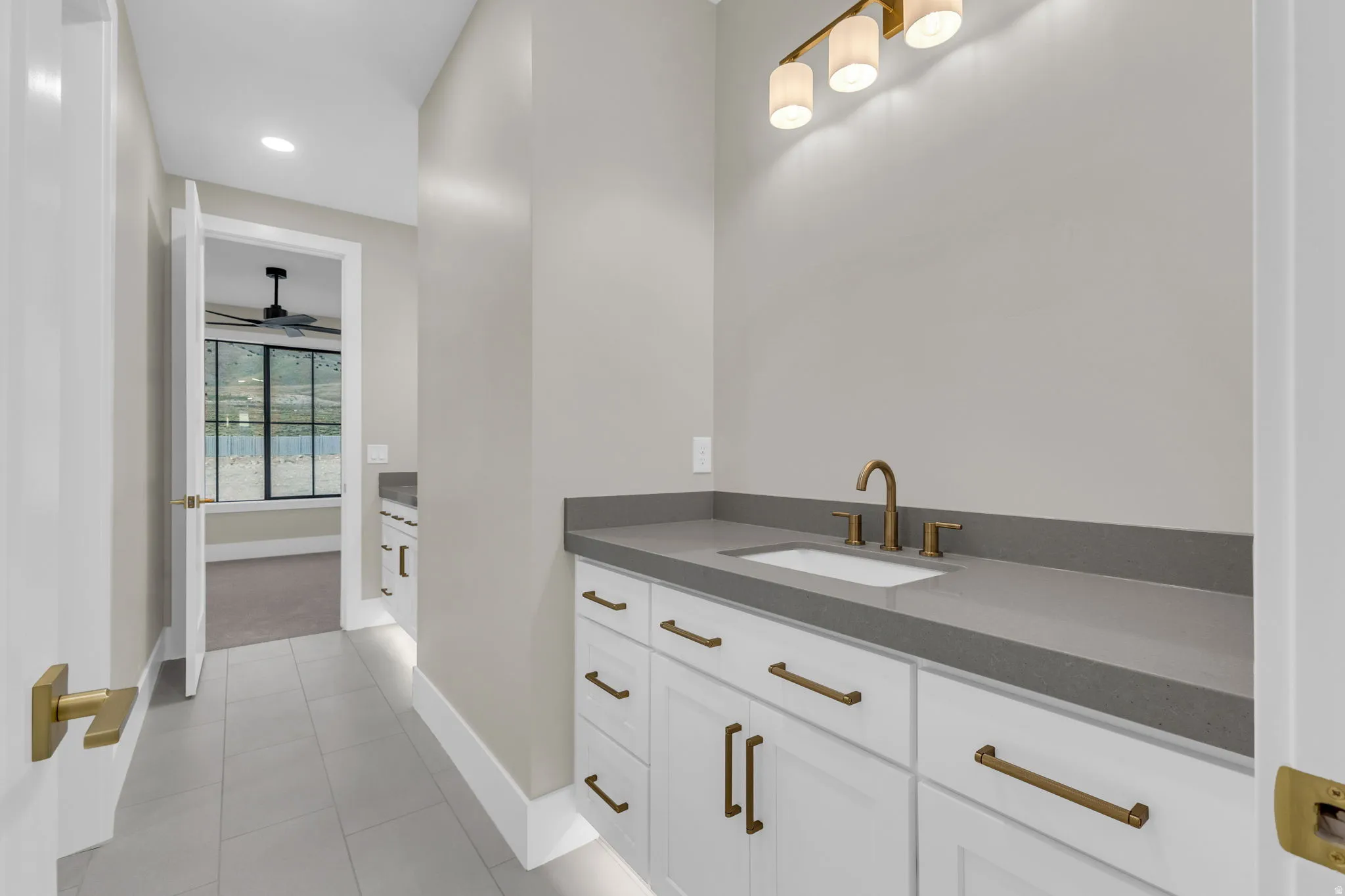 Vanity with a rectangular undermount sink, a bronze-finish faucet, and coordinating hardware on white cabinetry