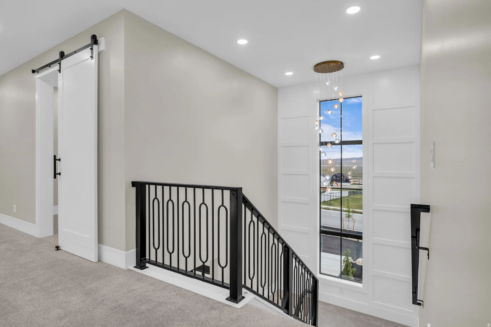 Upper-level landing featuring a large window, a modern chandelier, and recessed lighting