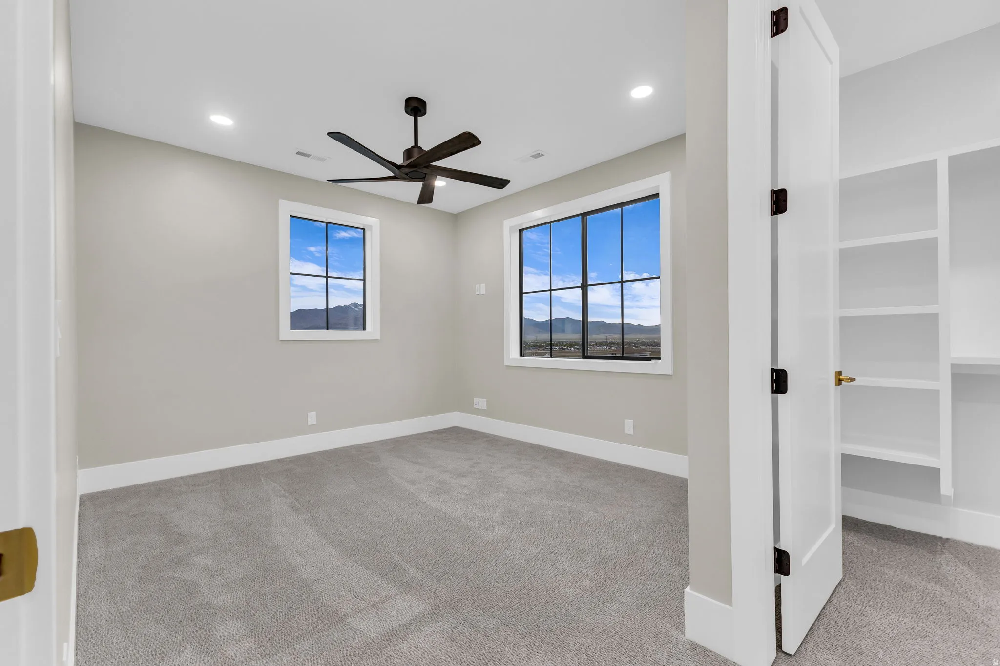 Room featuring two windows with black grilles, a dark-toned ceiling fan, recessed lighting, and light-toned carpeting