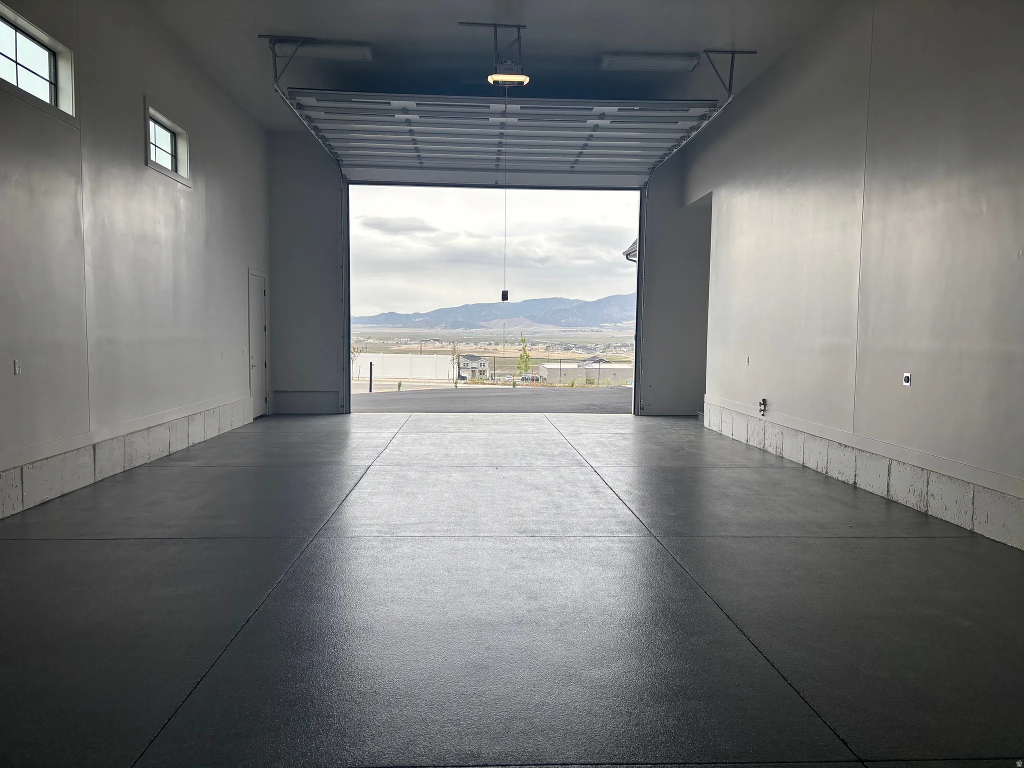 Spacious garage with an epoxy-coated concrete floor, white painted walls, and overhead lighting