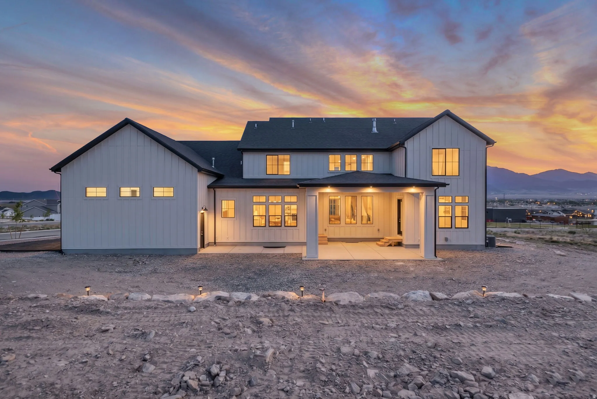 Modern farmhouse exterior featuring white vertical siding and dark-trimmed windows