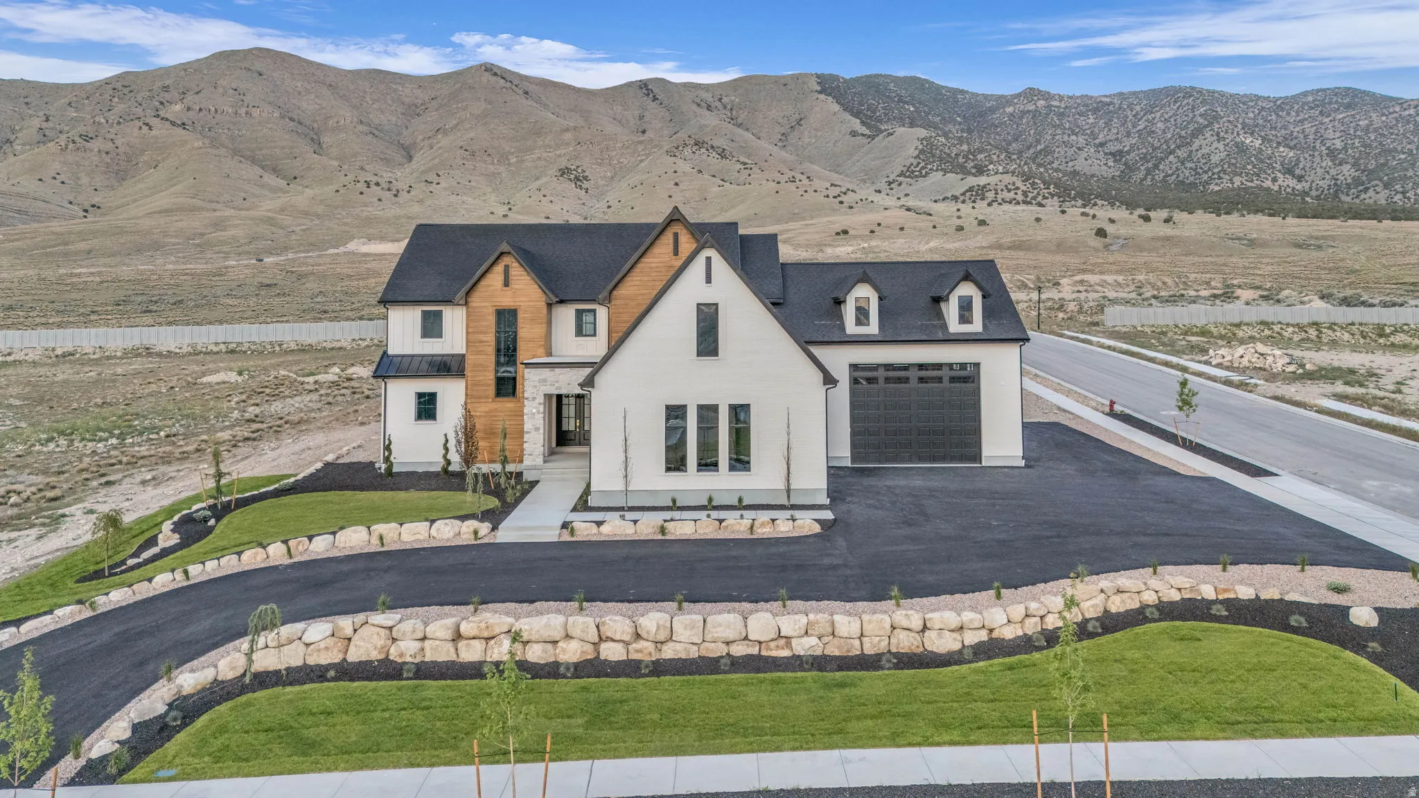 Contemporary residence featuring white and wood-finish siding, a dark roof, and an attached two-car garage