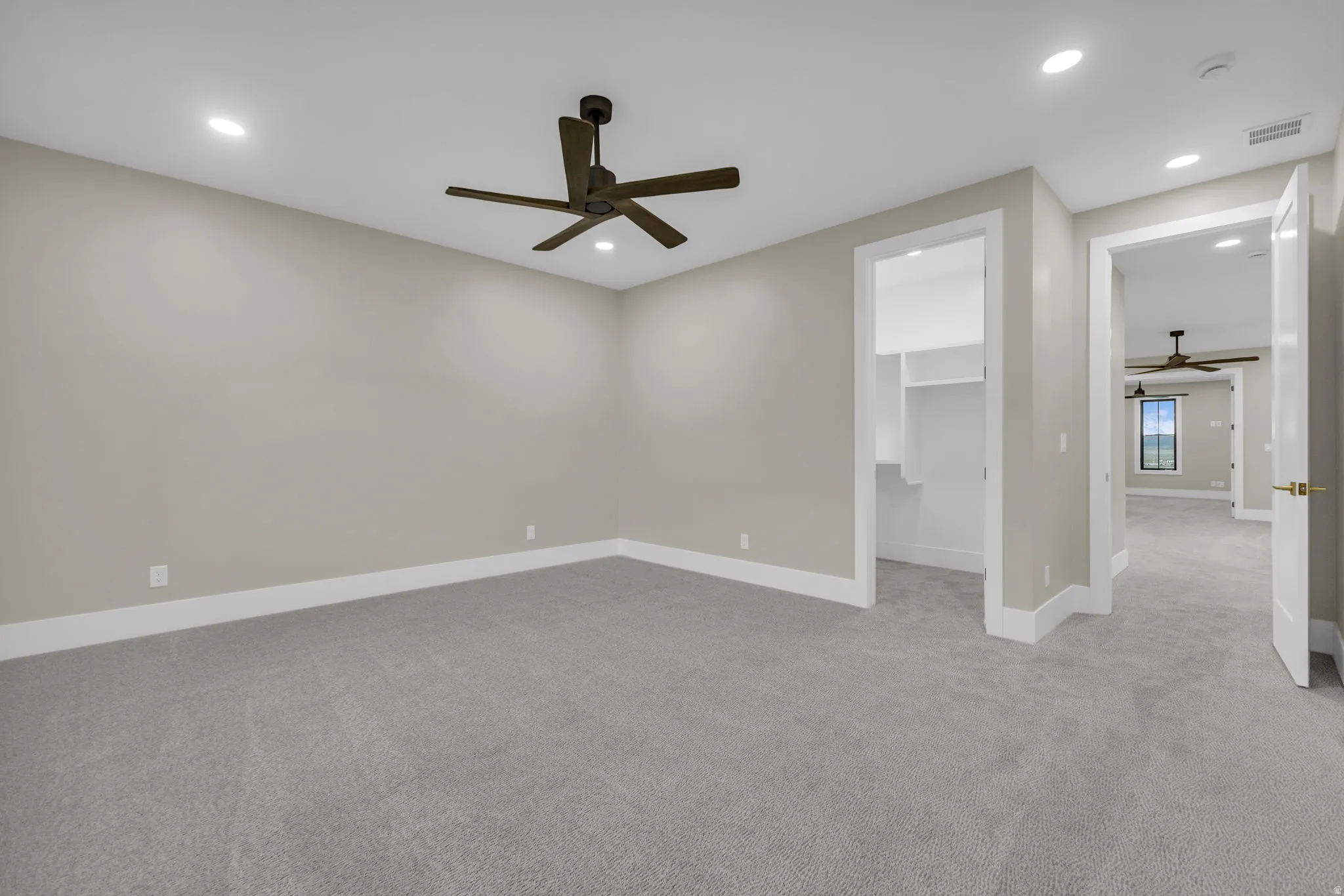 Spacious room featuring neutral carpet flooring, recessed lighting, a dark-toned ceiling fan, and white trim