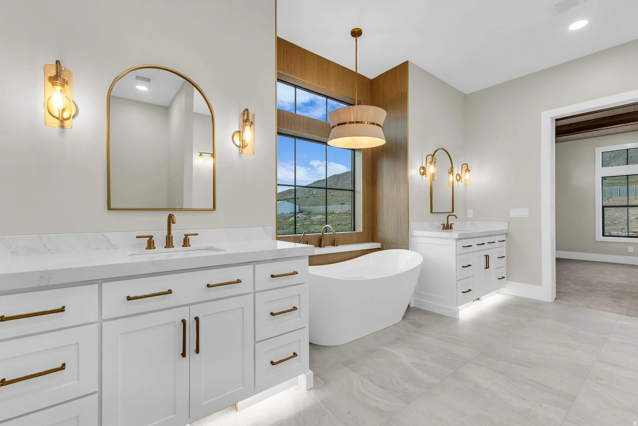 Spacious bathroom featuring dual vanities with white cabinetry and stone countertops