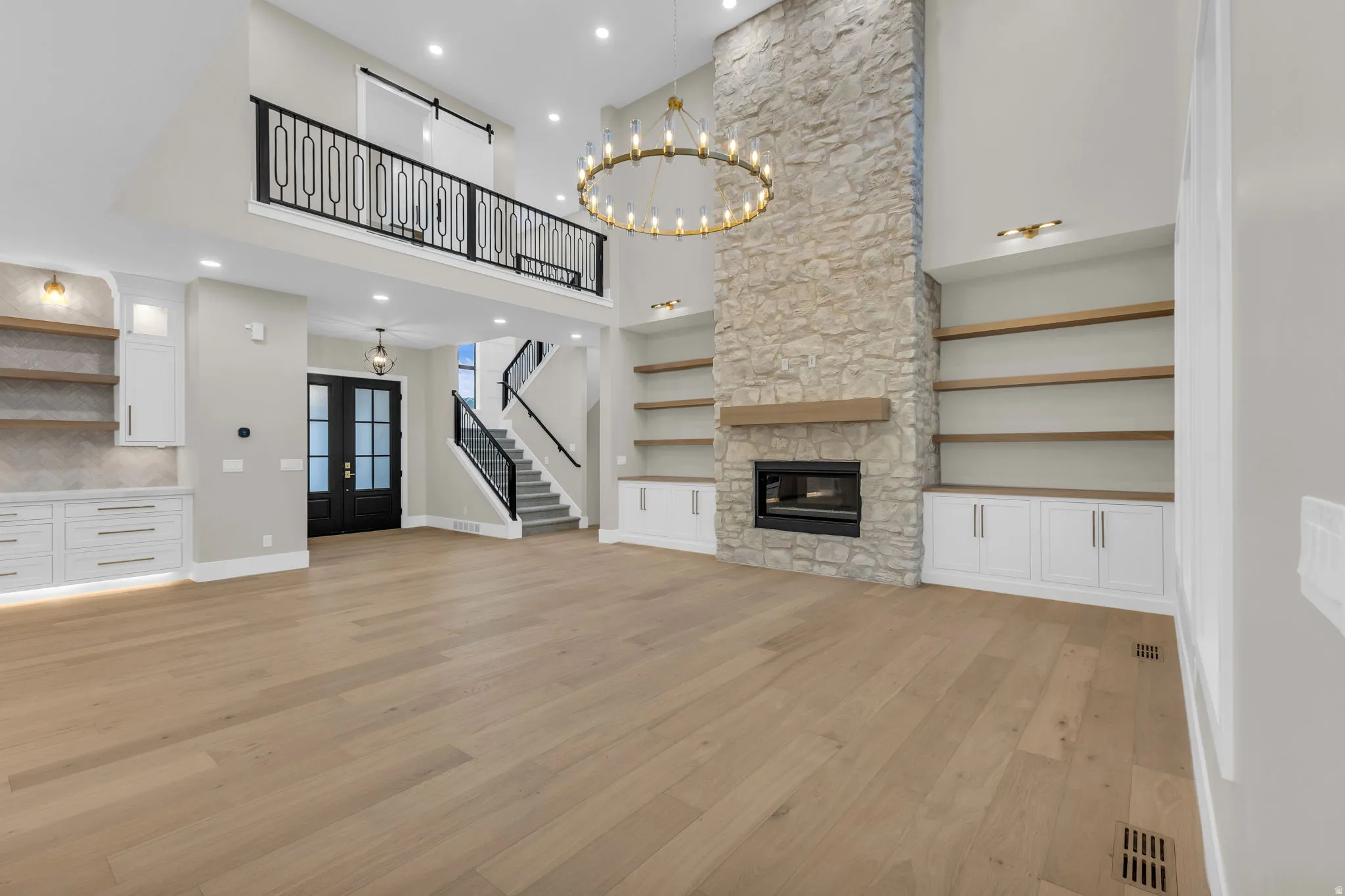 Great room featuring a floor-to-ceiling stone fireplace with a wood mantel, integrated electric fireplace, and high ceilings