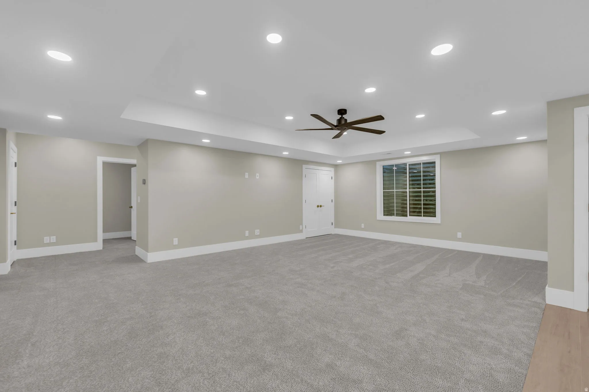 Spacious room featuring neutral paint, gray carpet, white trim, recessed lighting, and a ceiling fan