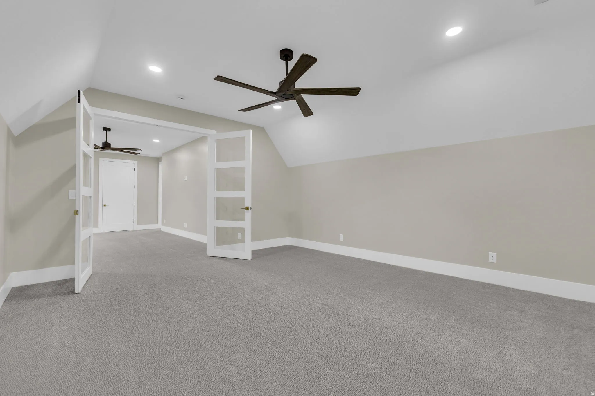 Spacious room featuring vaulted ceilings, recessed lighting, and a modern ceiling fan