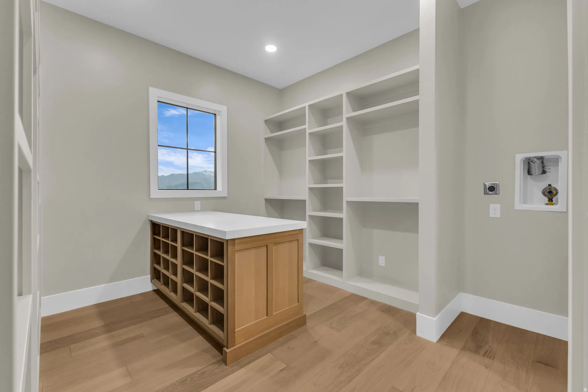 Dedicated utility space featuring extensive built-in shelving, a central island with integrated storage, and wood-finish flooring