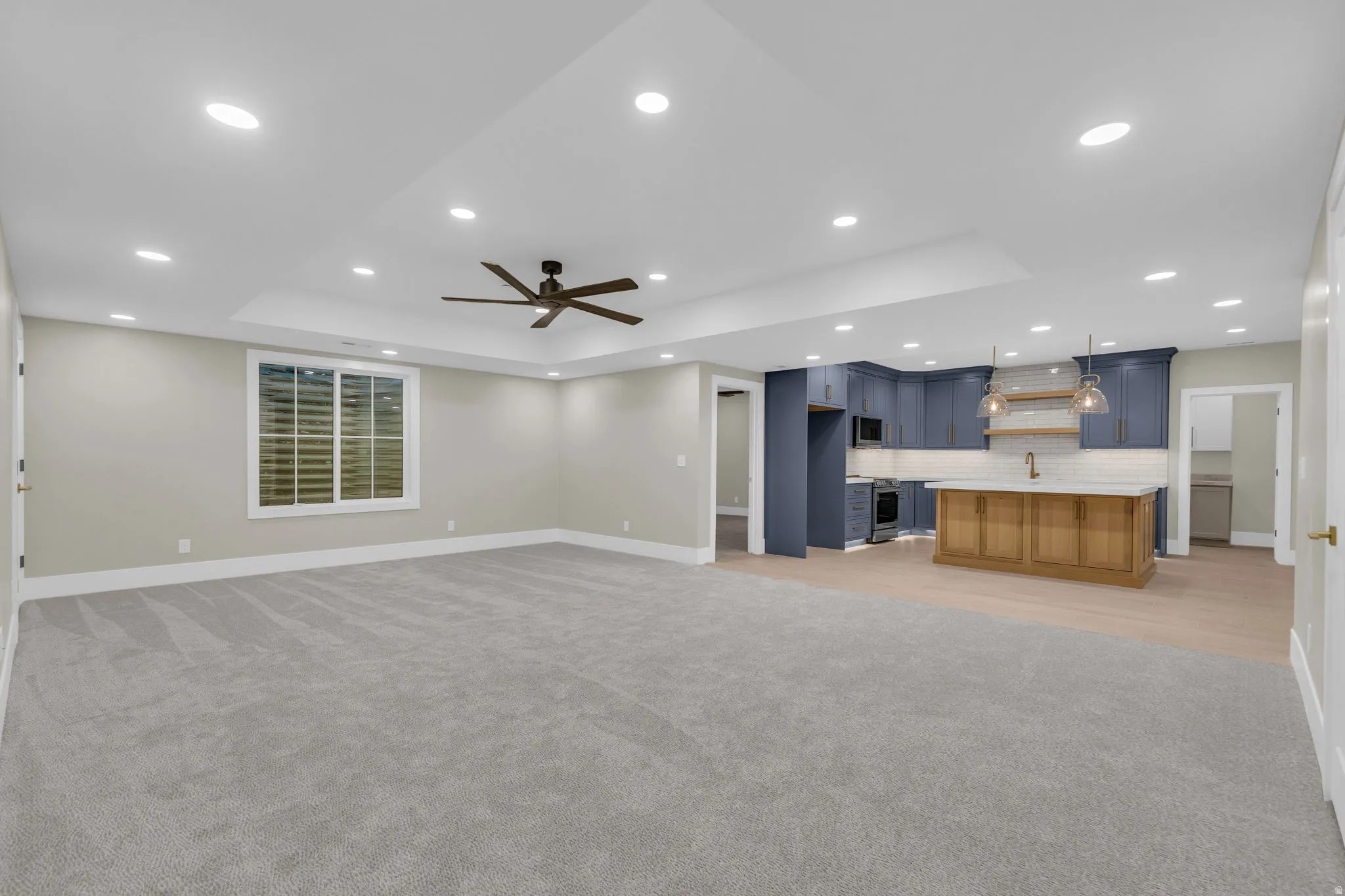Spacious open-concept living area featuring a tray ceiling with recessed lighting and a ceiling fan