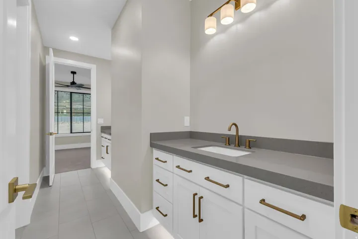 Vanity with a rectangular undermount sink, a bronze-finish faucet, and coordinating hardware on white cabinetry