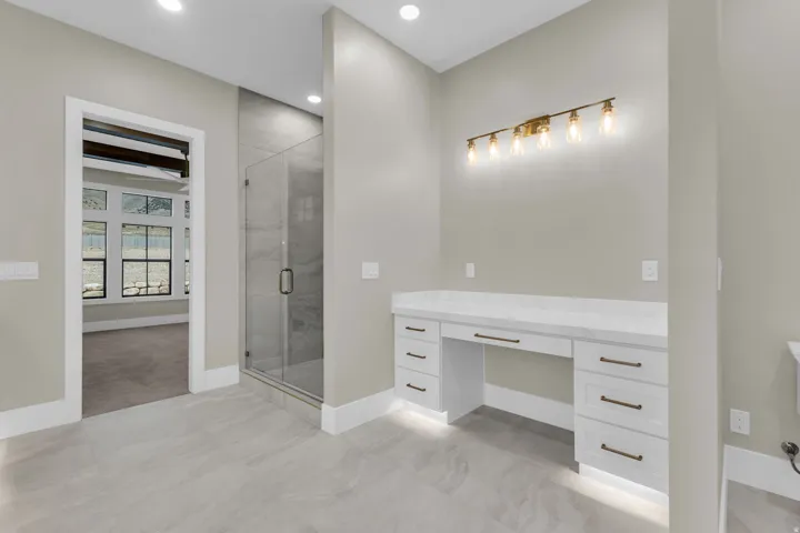 Spacious bathroom featuring a built-in vanity with a light-colored countertop, white cabinetry with dark hardware, and a multi-bulb light fixture