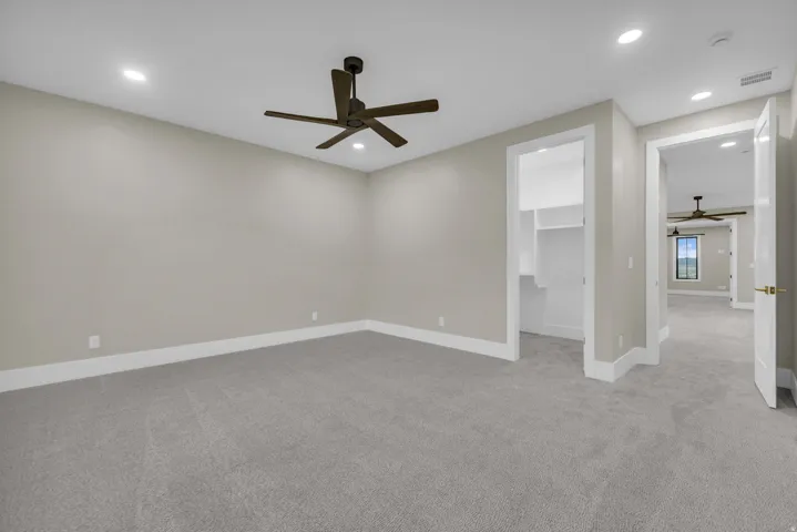 Spacious room featuring neutral carpet flooring, recessed lighting, a dark-toned ceiling fan, and white trim