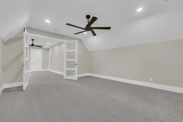 Spacious room featuring vaulted ceilings, recessed lighting, and a modern ceiling fan
