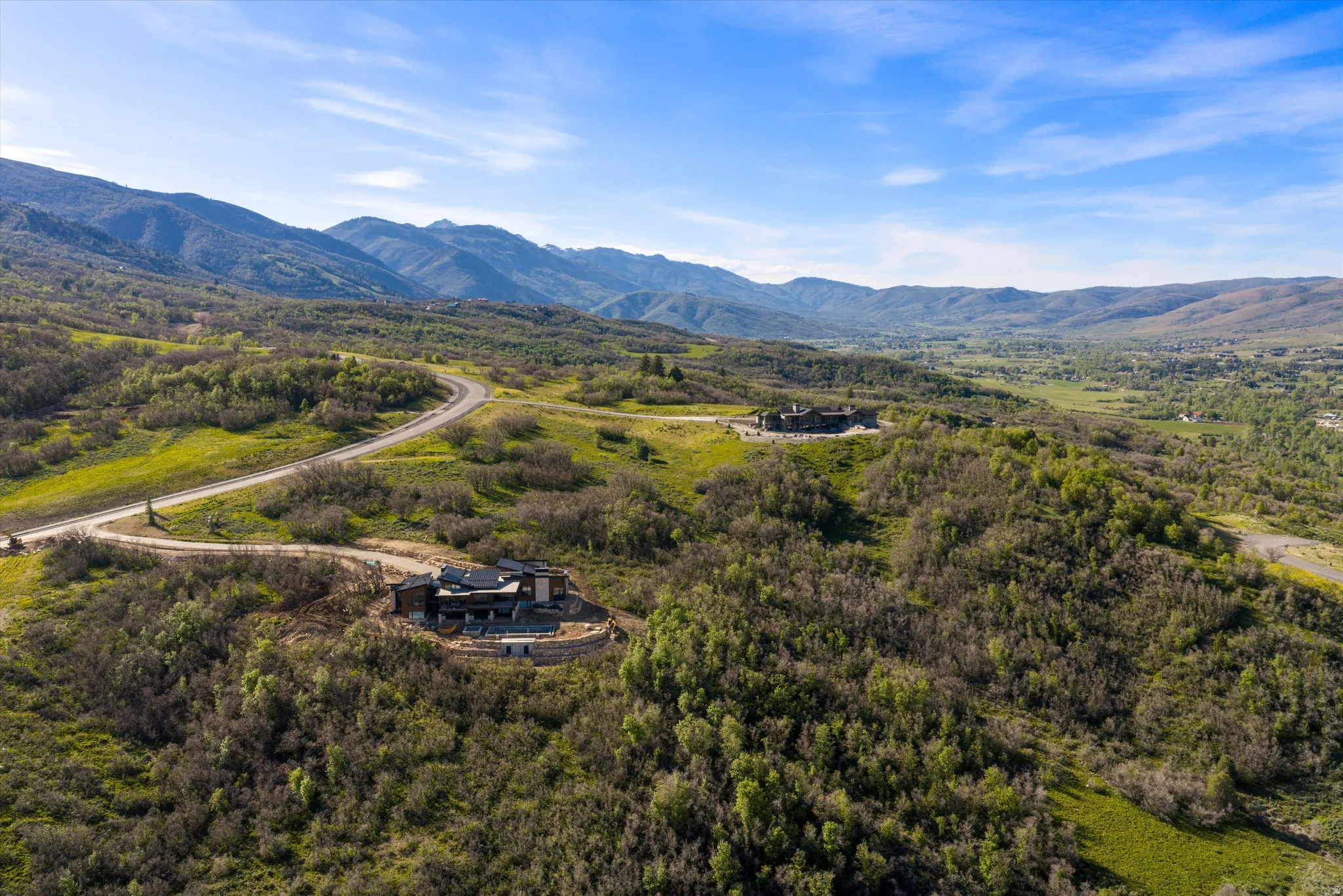 Expansive mountain landscape with a modern architectural residence featuring a dark facade and multiple terraces
