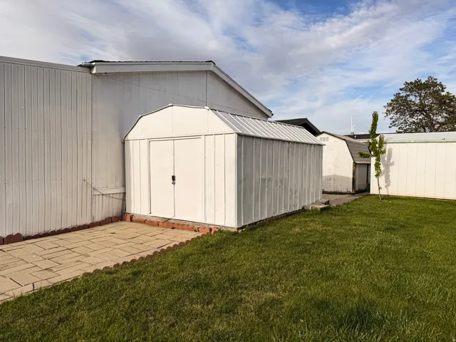 White storage shed featuring a gambrel roof and double doors
