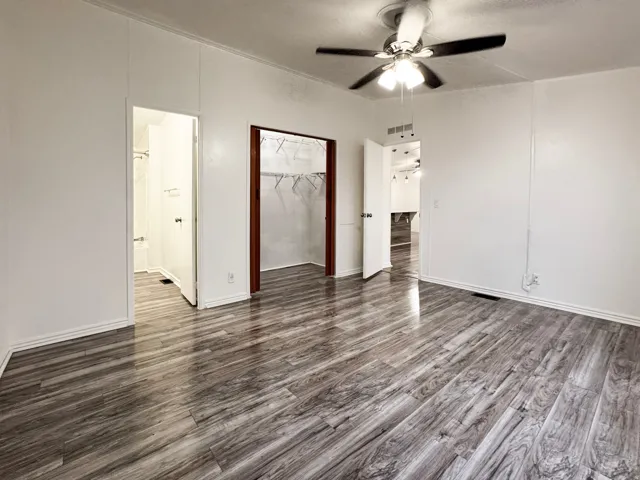 Master Room featuring wood-finish flooring, white walls, and a ceiling fan with integrated lighting