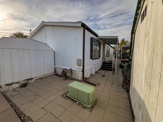 White siding exterior with black trim windows, a covered entry with steps, and a paved walkway