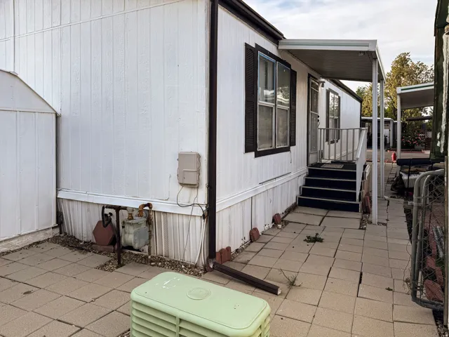 Side entrance featuring a covered patio, exterior steps, and a white aluminum shed
