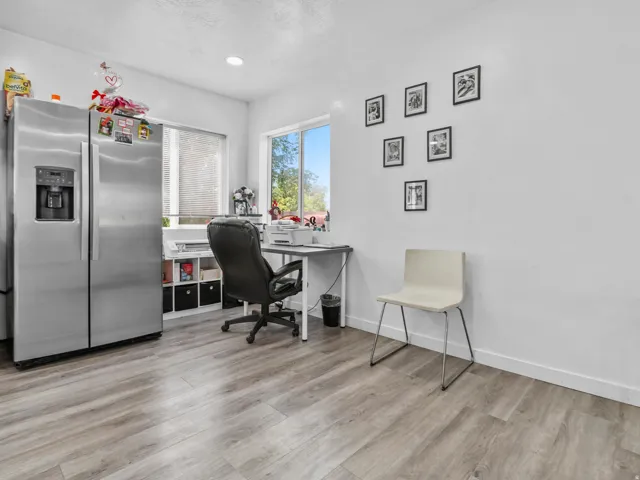 Bright interior space featuring wood-finish flooring, white walls, and a large window providing natural illumination