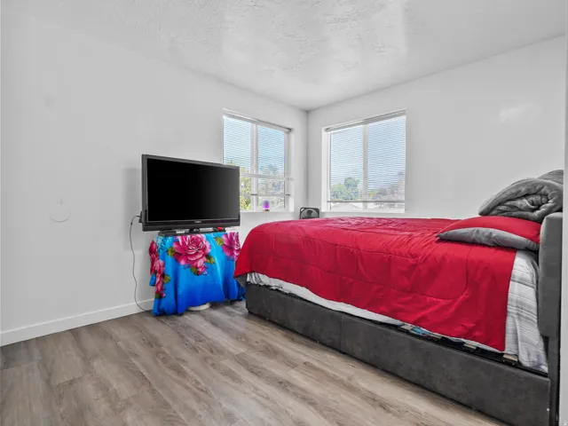 Room with wood-finish flooring, white walls, and two windows with horizontal blinds