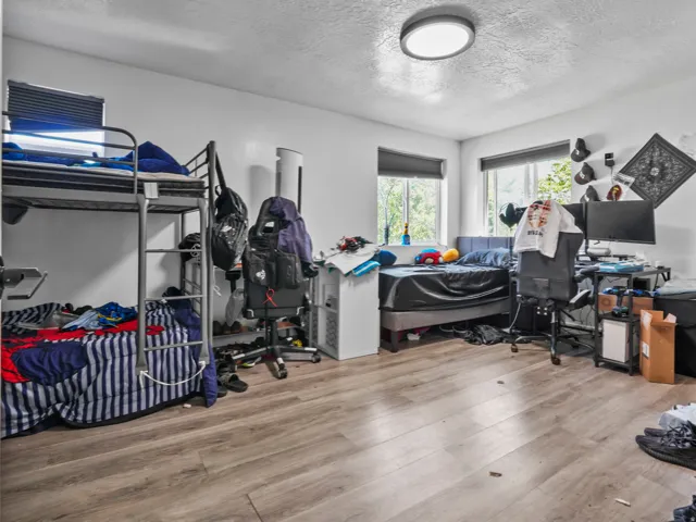 Bright room featuring wood-finish flooring and multiple windows with blinds