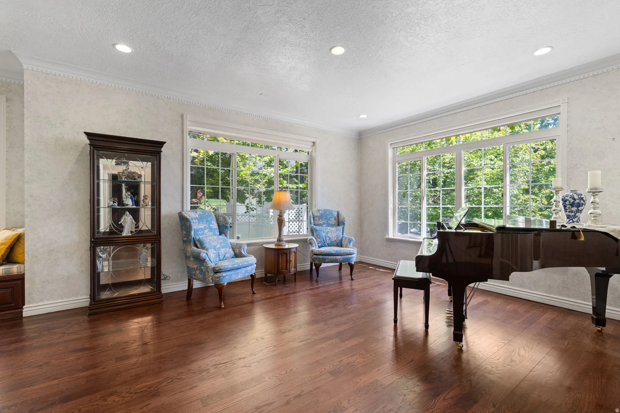 Spacious sitting oom featuring rich wood-finish flooring, recessed lighting, and large windows with transom details