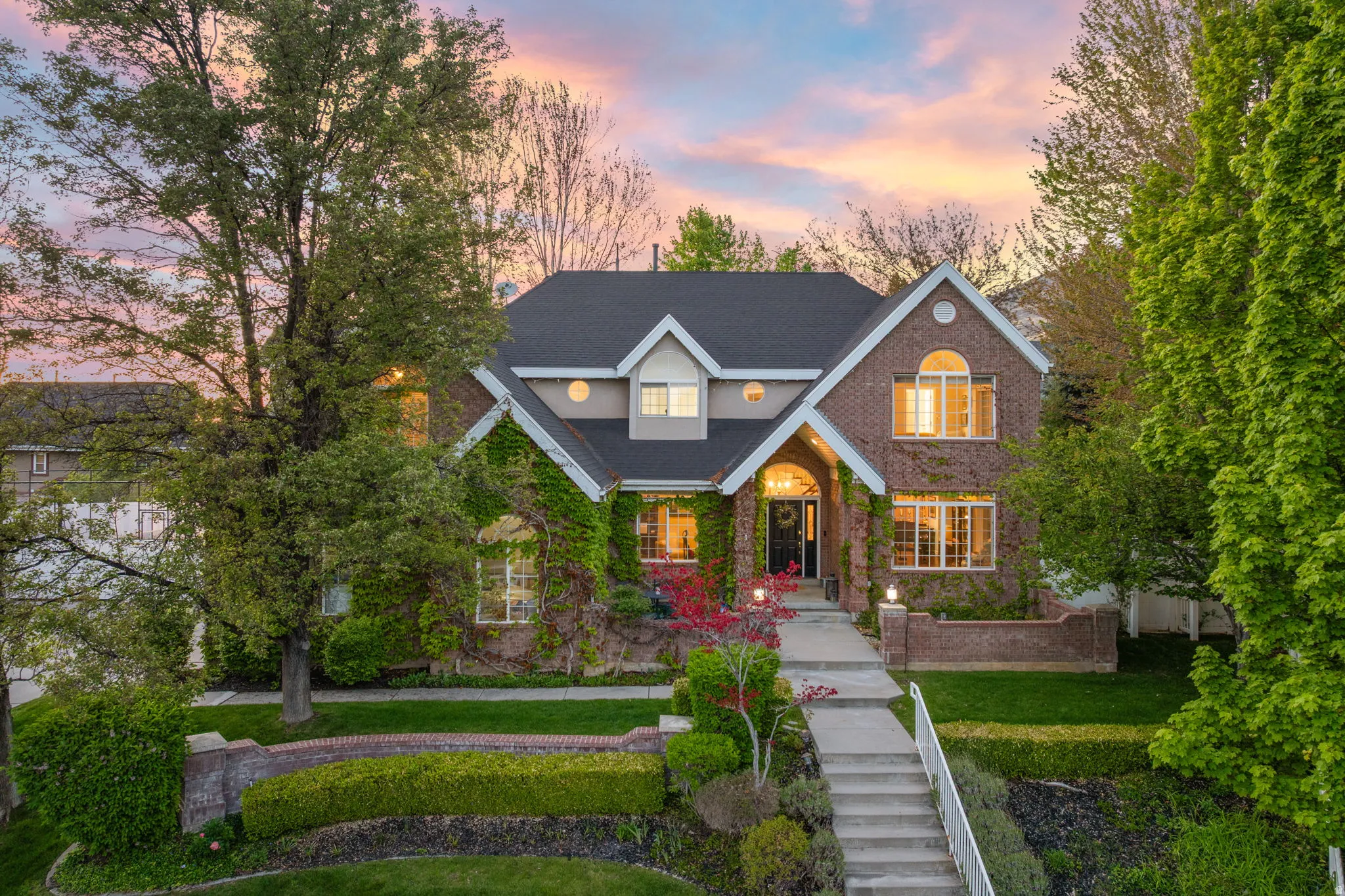 Brick exterior featuring a gabled roofline, arched entry, prominent windows, and mature climbing ivy