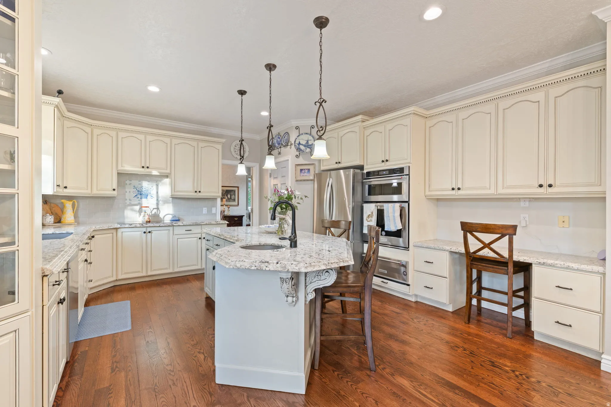 Kitchen featuring an angular island with a built-in sink, granite countertops, wood flooring, and stainless steel appliances