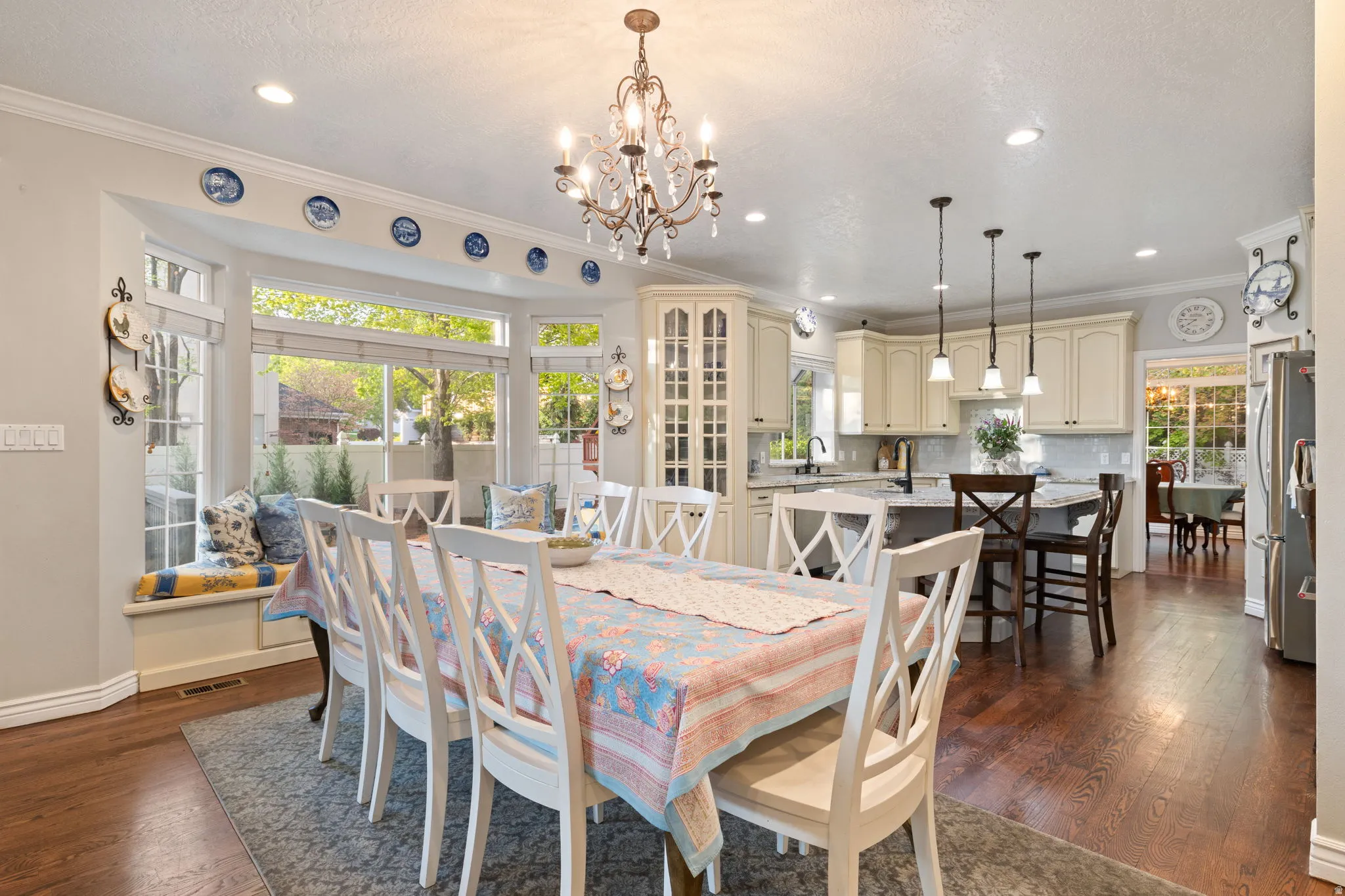 Open-concept living area featuring rich wood flooring, a decorative chandelier, recessed lighting, and a bay window with an integrated window seat