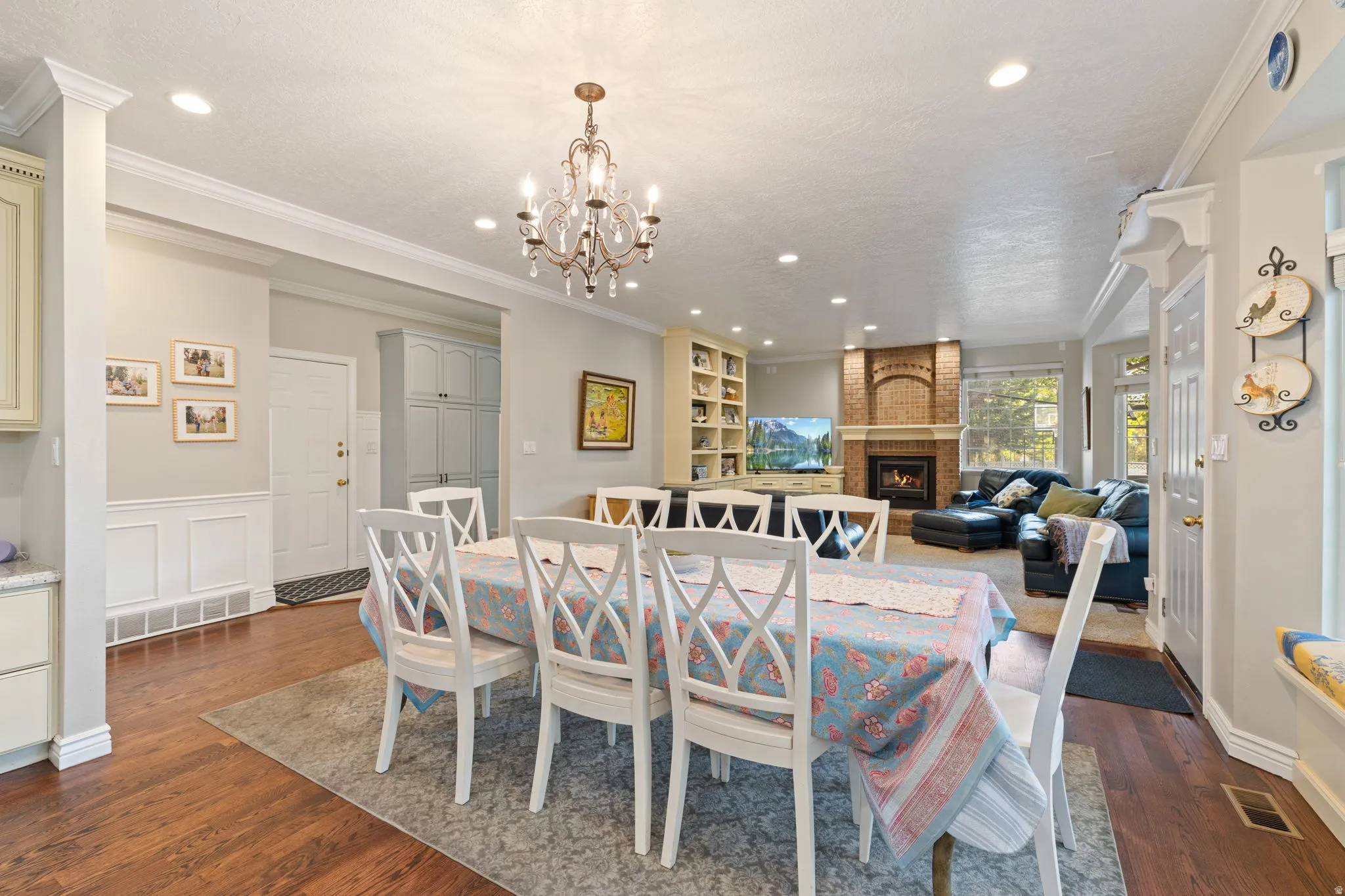 Open-concept dining area featuring woo flooring, a chandelier, recessed lighting, wainscoting, and a bay window with an integrated window seat