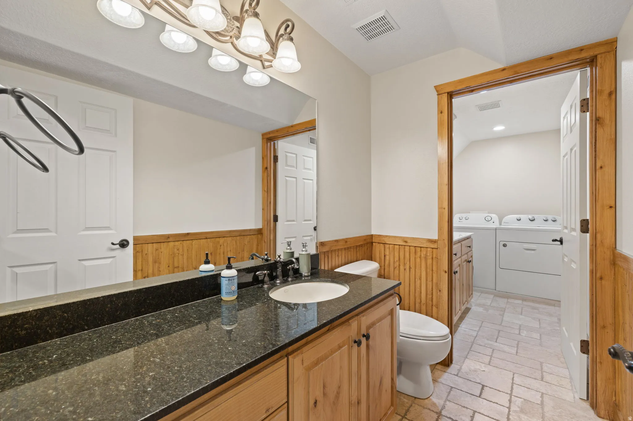 Bathroom featuring a wood-finish vanity with granite countertop and an undermount sink