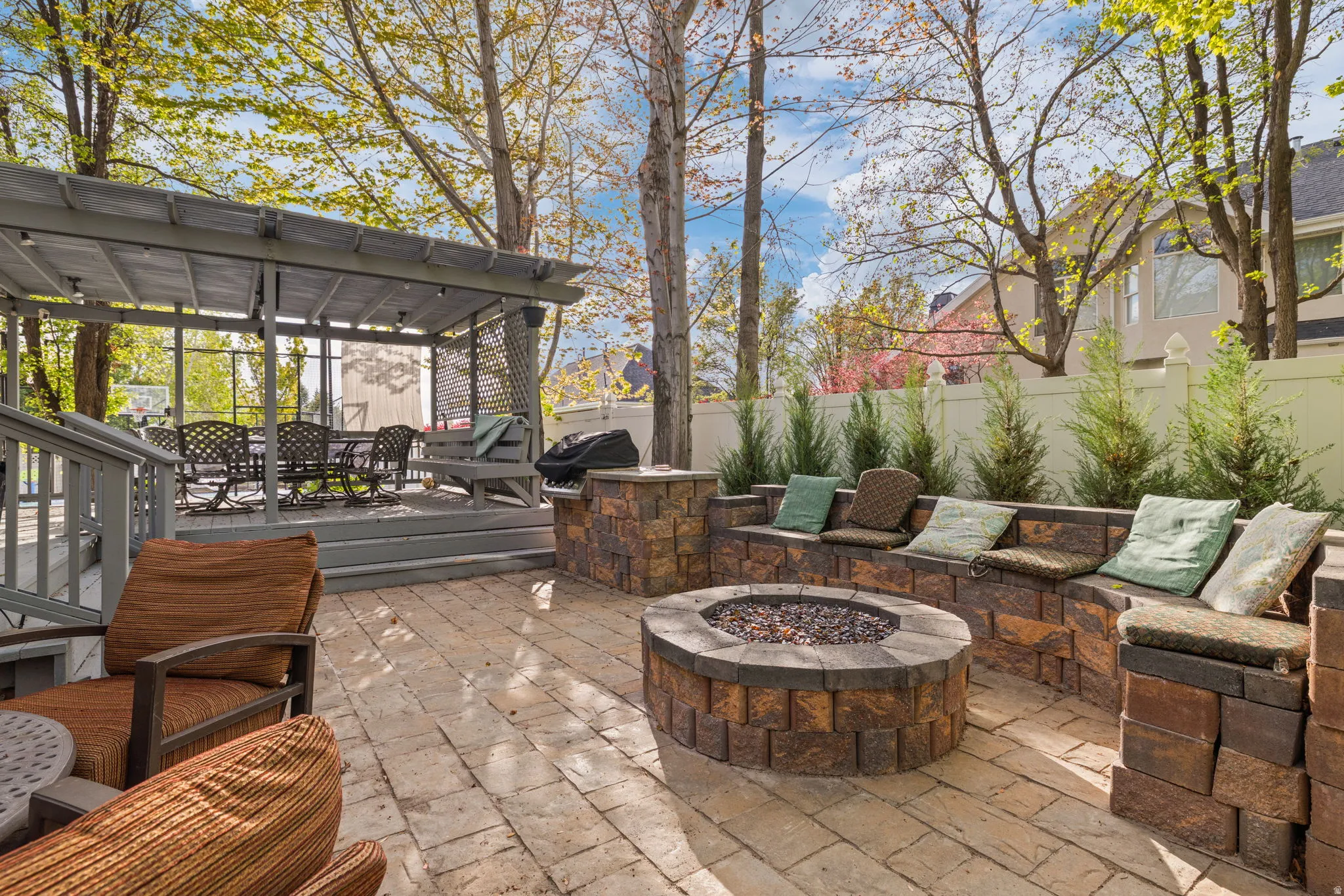 Expansive paver patio featuring a built-in fire pit with a stone surround