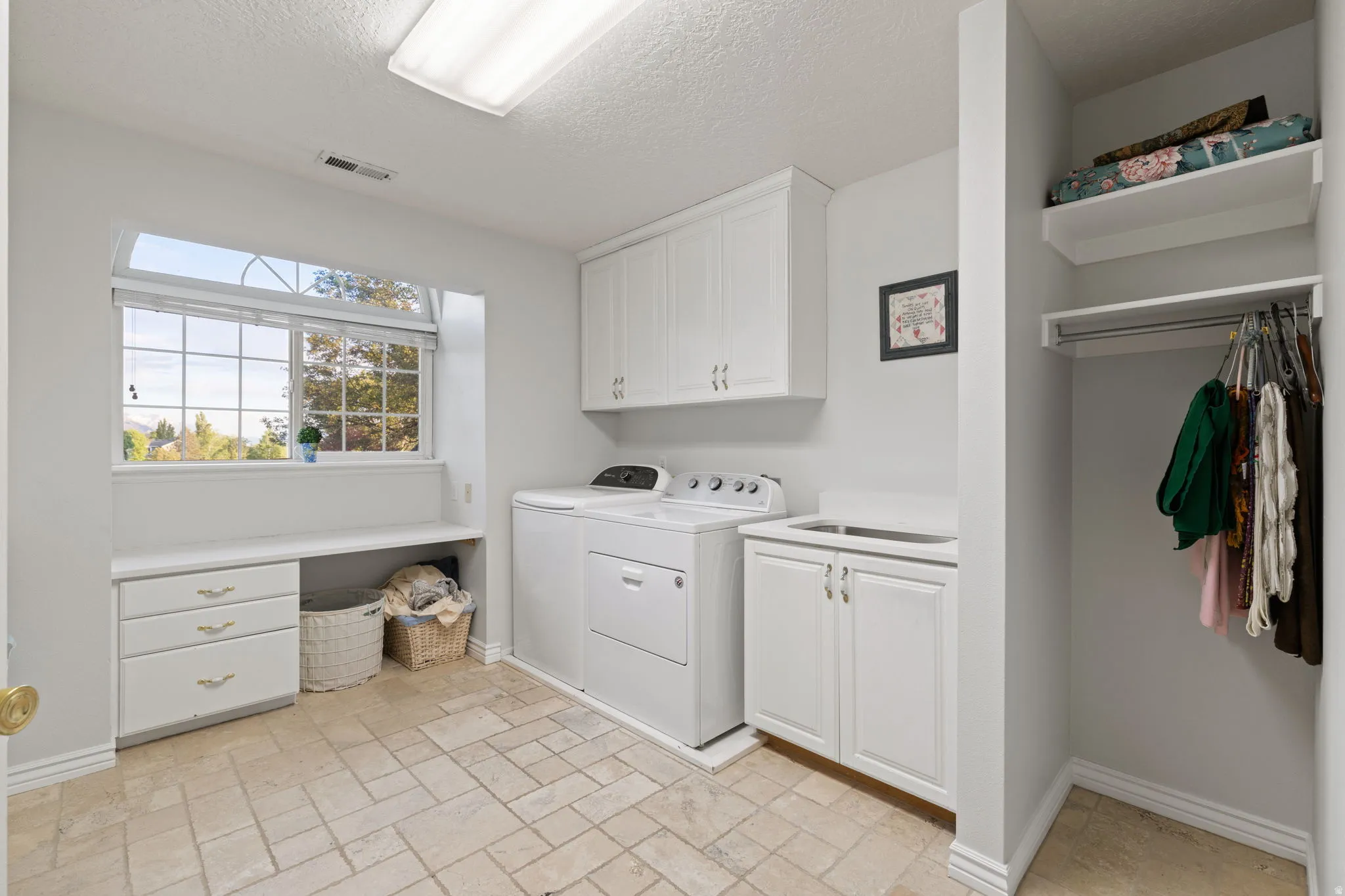 Large laundry room featuring tile flooring and white cabinetry for storage