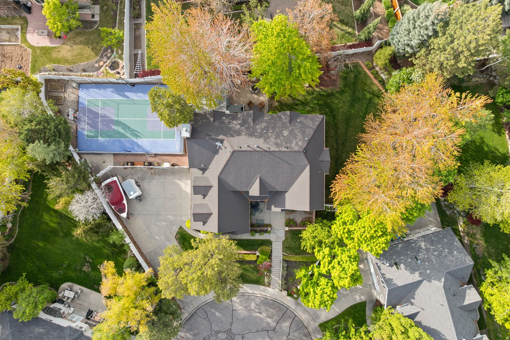 Spacious property featuring a tennis court, extensive paved driveway, and mature landscaping