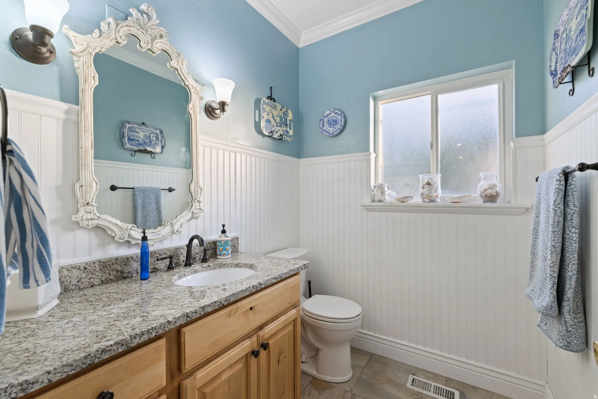Bathroom featuring a wood-finish vanity with a light granite countertop and undermount sink