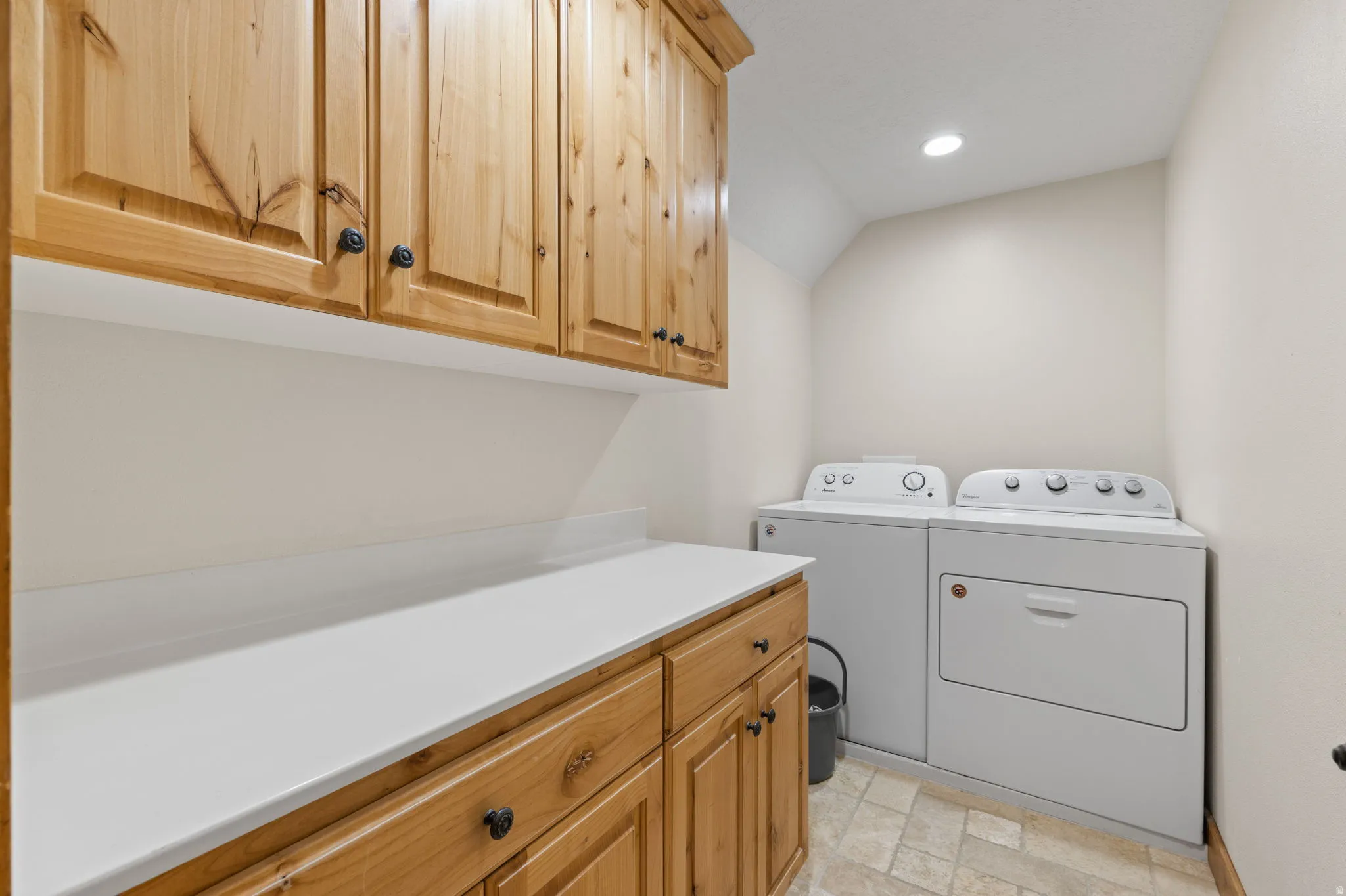 Laundry area featuring upper and lower wood cabinetry, white countertops, recessed lighting, and tile flooring