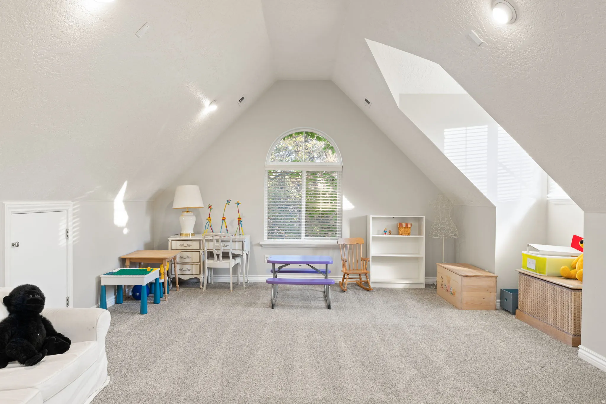 Expansive loft featuring light gray carpet flooring and a vaulted ceiling