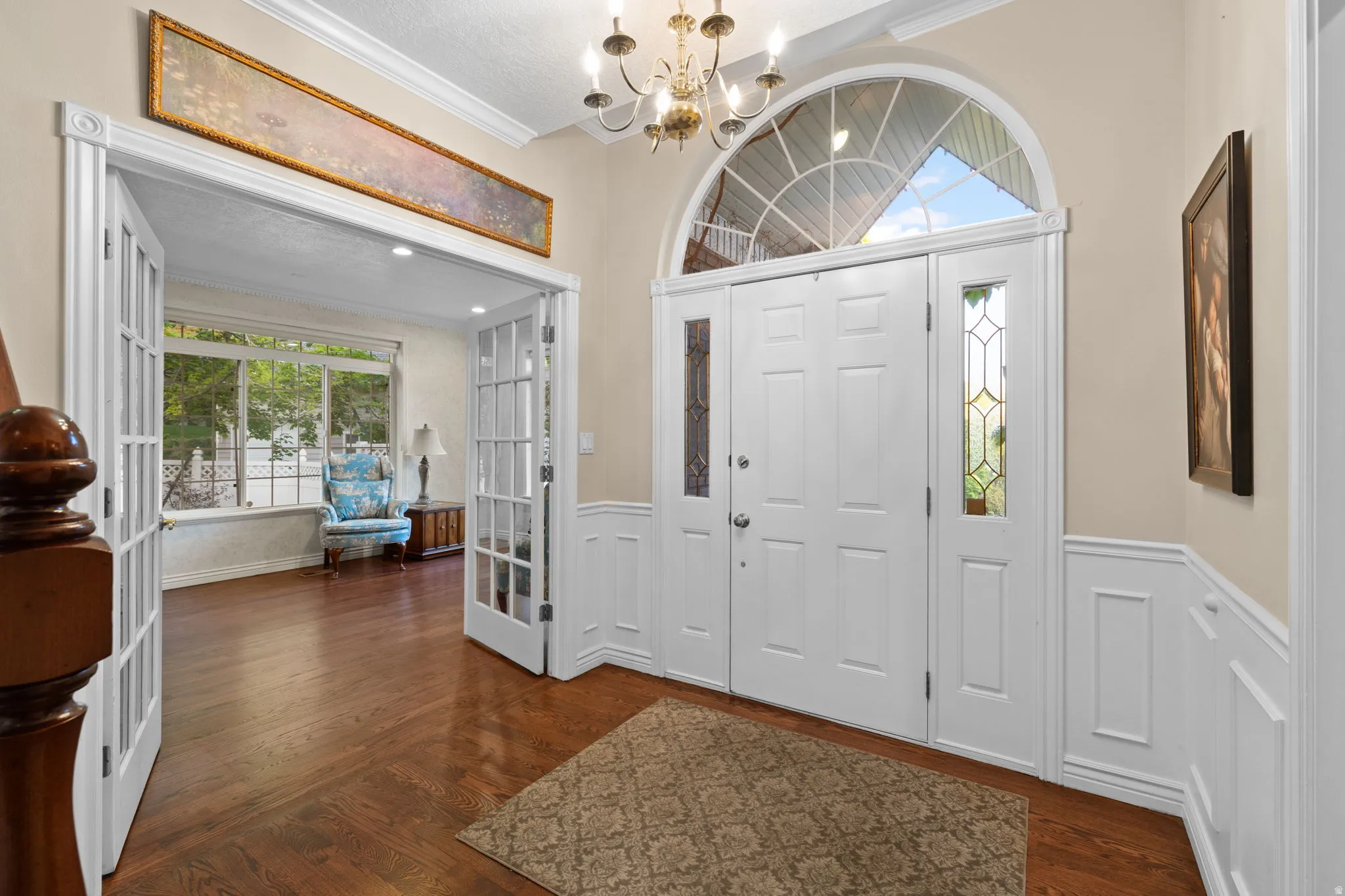 Grand entryway featuring French double doors, an arched transom window, and decorative leaded glass sidelights