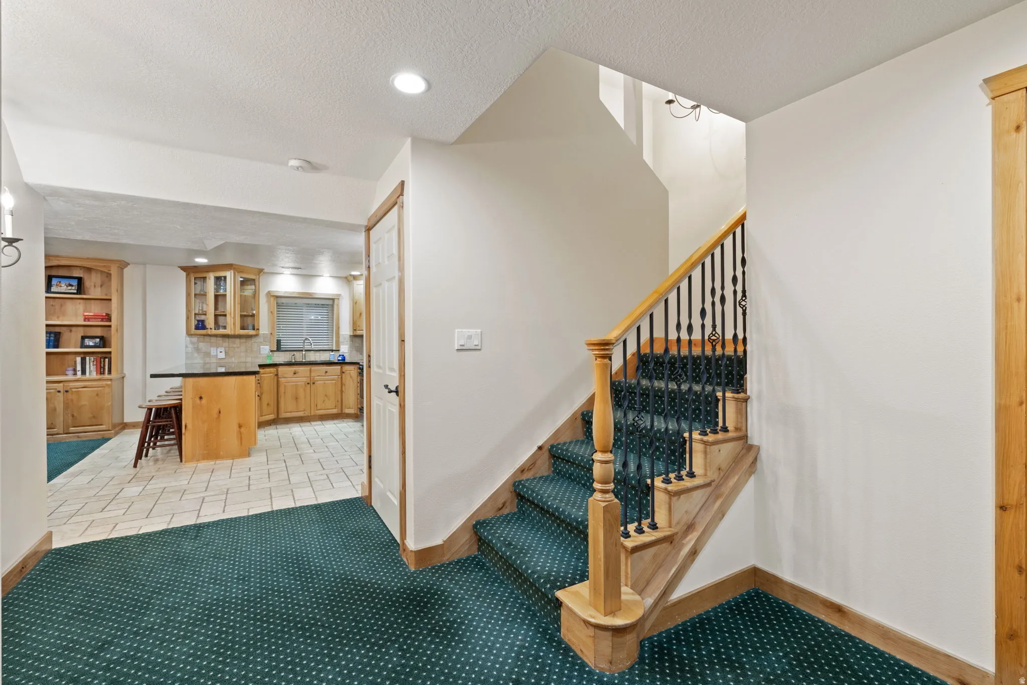 Staircase and landing featuring wood newel posts, handrail, and wrought iron balusters