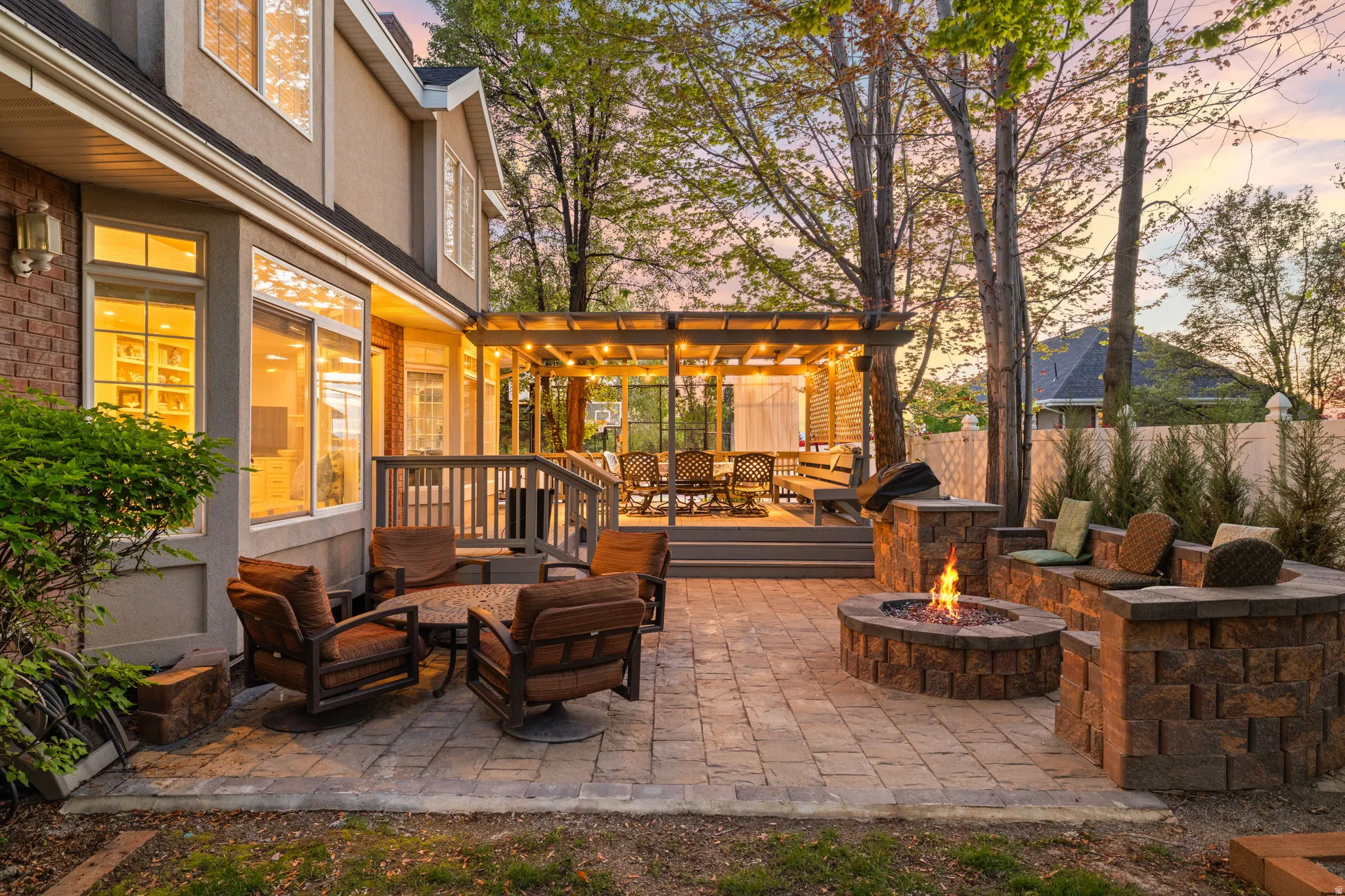 Expansive backyard featuring a paver patio with a built-in fire pit, stone seating, and a multi-level deck