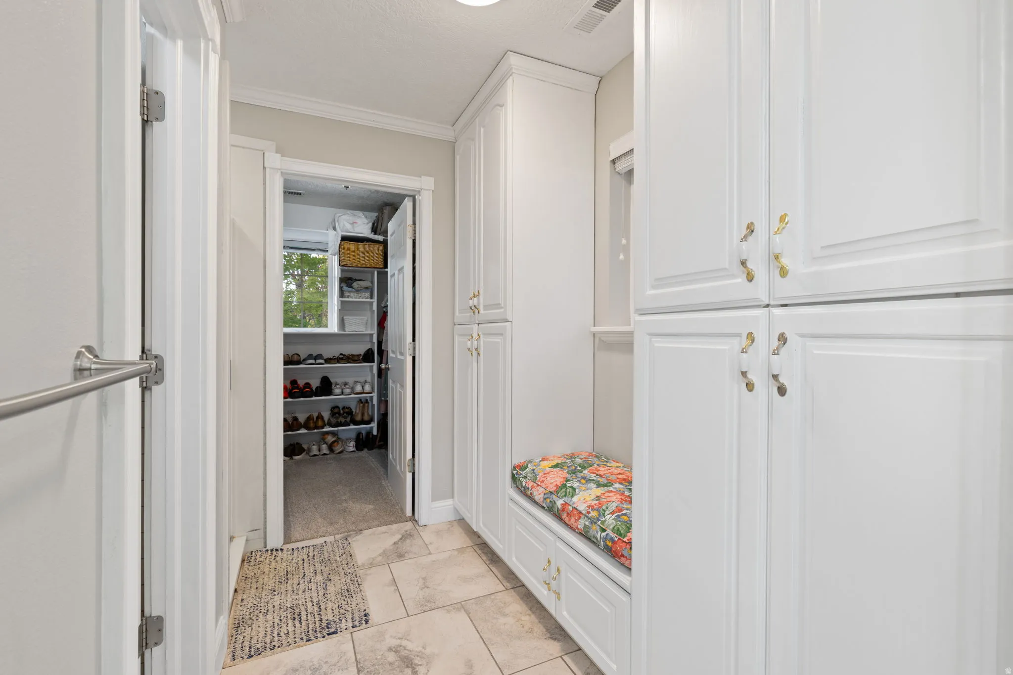 Primary bathroom featuring built-in white cabinetry, a built-in bench, and heated tile flooring
