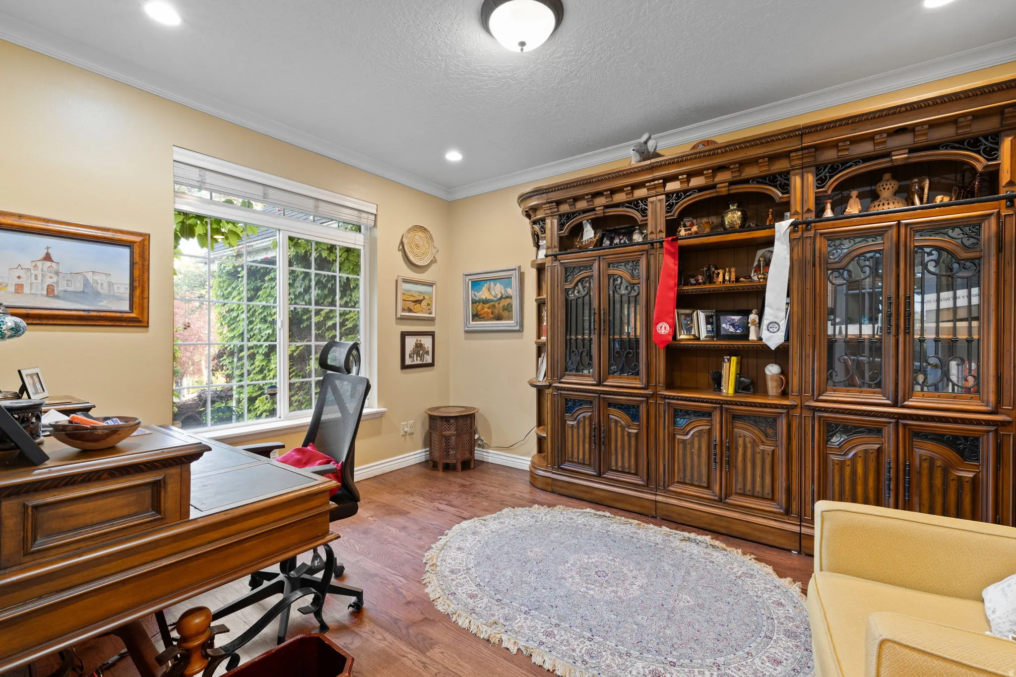 Spacious office featuring wood flooring and a decorative built-in wall unit with glass-front cabinetry